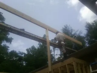 Carpenter setting a ridge beam over a new addition frame — Ice Dam Removal by Roofing Brothers in Friendsville