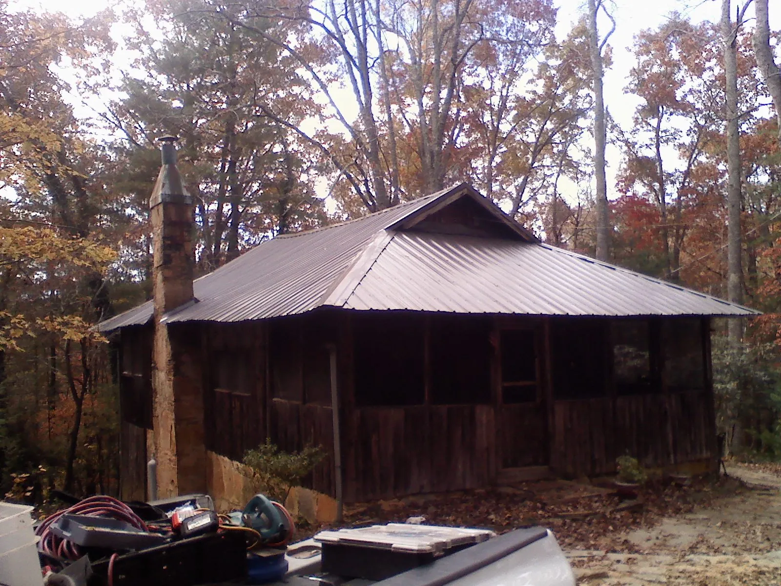 Brown metal hip roof on an old cabin with a stone chimney in Friendsville
