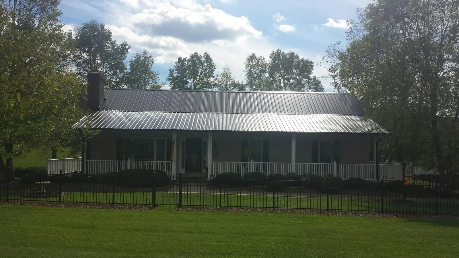Gray metal roof on a brick ranch with a full width front porch — Gutter Guard Installation work by our crew in Friendsville